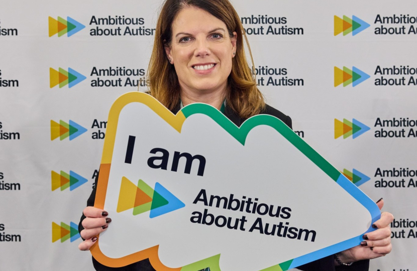 Caroline holding a plaque saying "I am Ambitious about Autism"