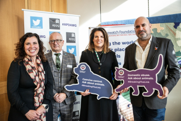 Caroline with representatives of the Naturewatch Foundation, holding a dog plaque, which reads "Coercive Control. Ask about animals. #BreakingTheLink"