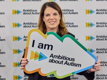 Caroline holding a plaque saying "I am Ambitious about Autism"